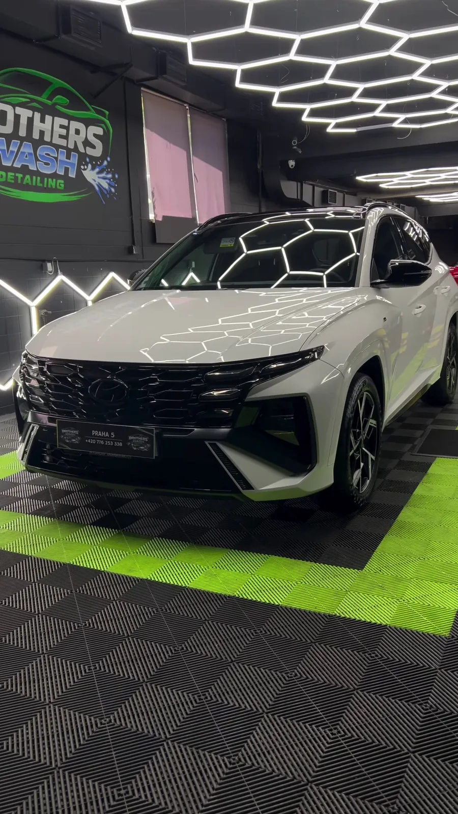 Lesklý bílý Hyundai Tucson pod hexagonálními světly